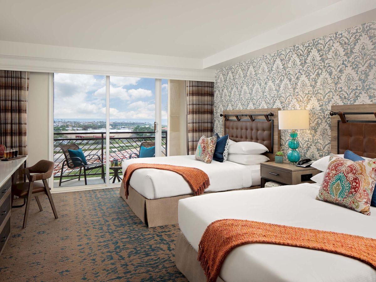 Two modern hotel rooms with twin beds, stylish decor, a balcony view, patterned wallpaper, and a desk; bright, inviting, and overlooking a cityscape.